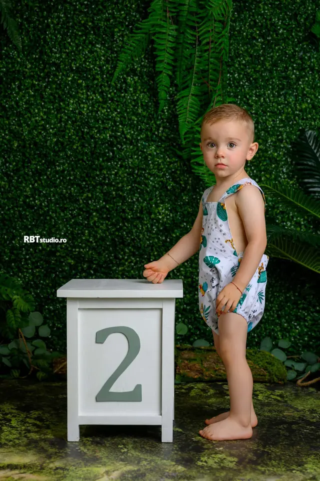 Copil de 2 ani lângă o cifră decorativă, decor verde